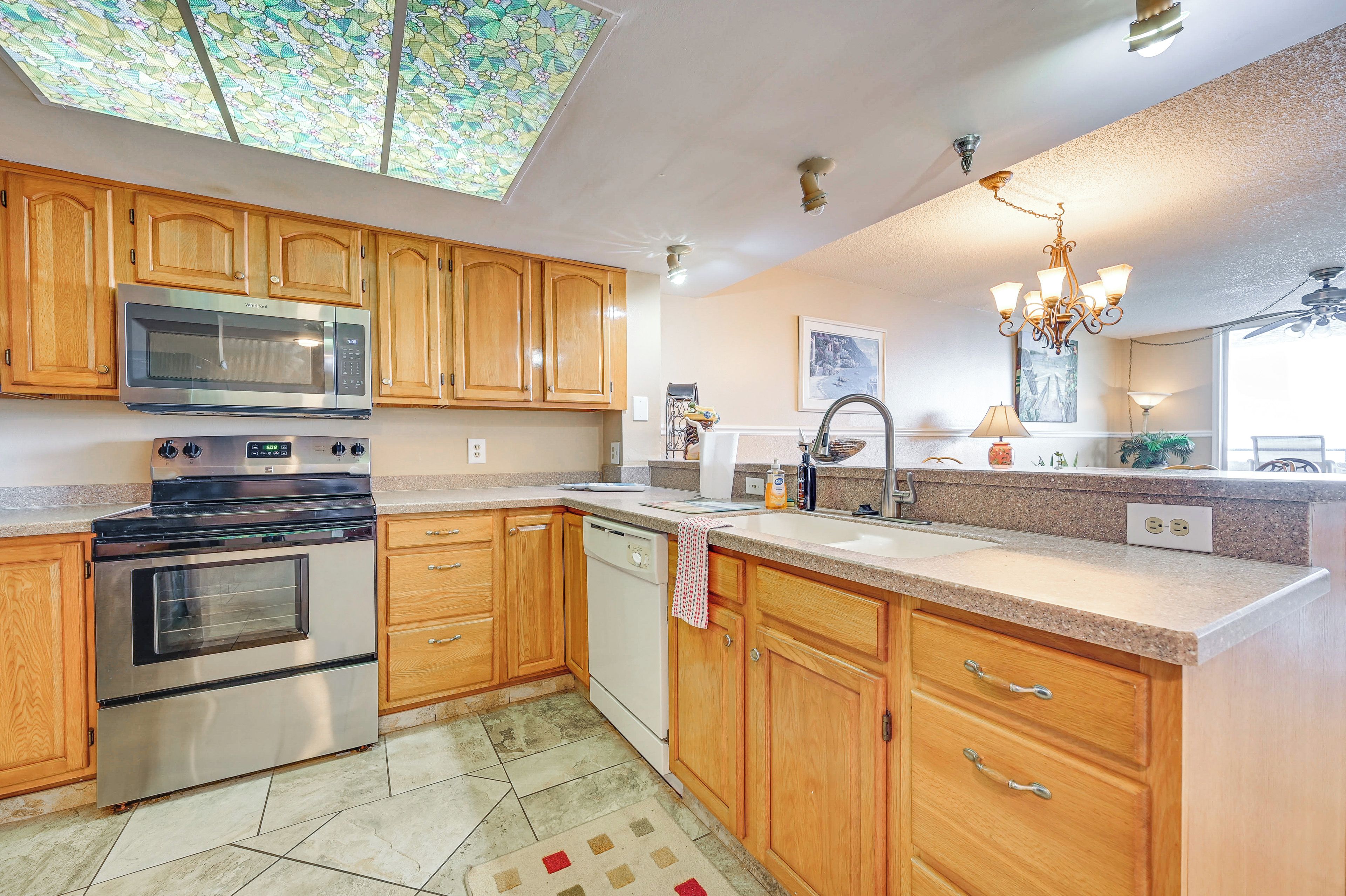 A kitchen with wooden cabinets, a stainless steel microwave, a stove, and a dishwasher.
