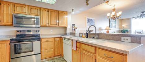 A kitchen with wooden cabinets, a stainless steel microwave, a stove, and a dishwasher.