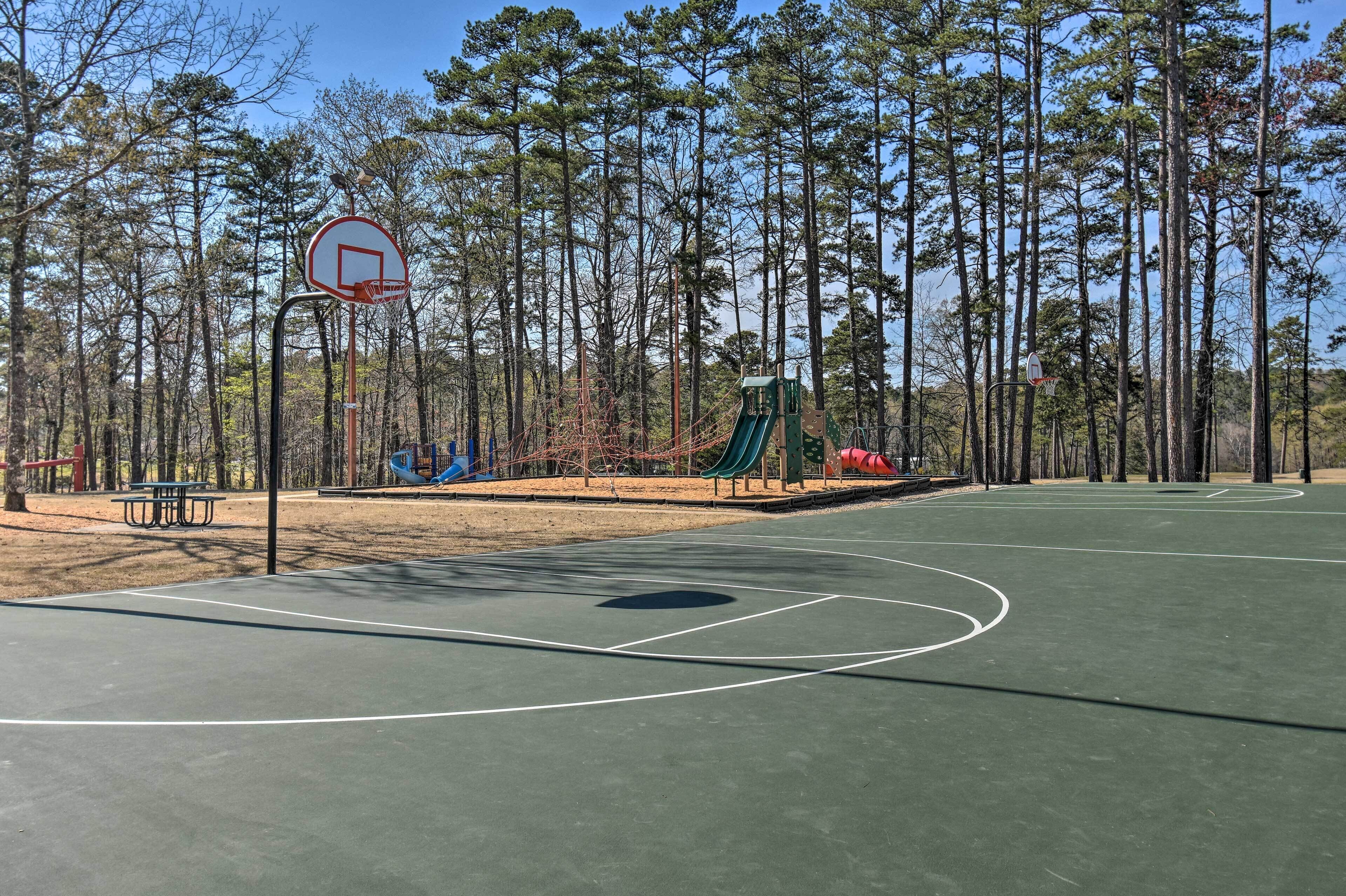 Een basketbalveld buiten met een picknicktafel en speeltoestellen.