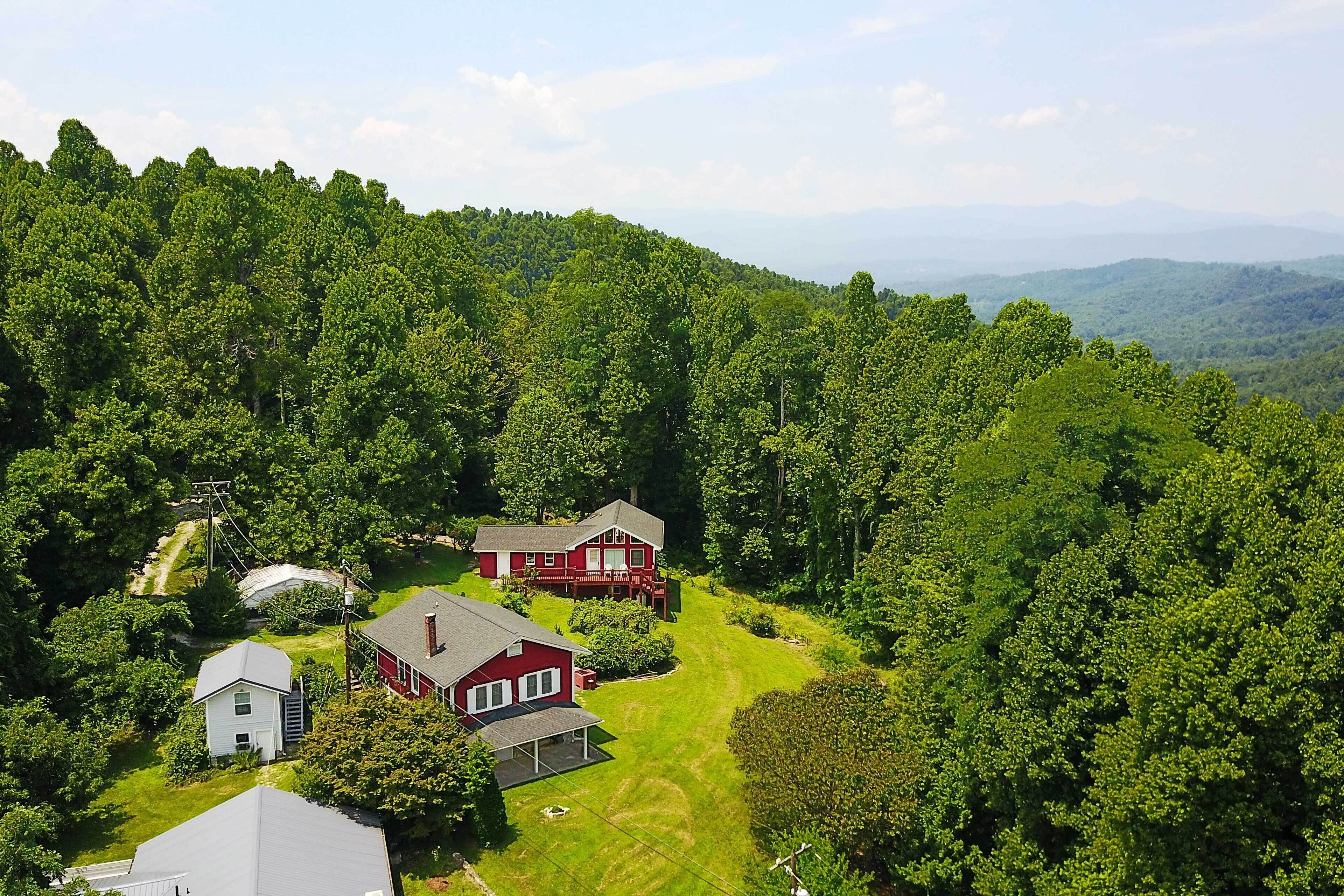 A residential area with two houses surrounded by dense forest.