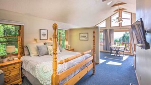A spacious bedroom with a large bed, a wooden headboard, a ceiling fan, and a view of the outdoors through large windows. - Hendersonville 'cantrell Cottage' - Smoky Mtn View (Hendersonville)
