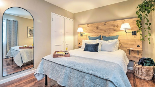 Ein Schlafzimmer mit einem großen Bett, einem Holz-Kopfteil, Nachttischlampen, einem Spiegel und einem Nachttisch mit einem Frühstücksbrettchen.