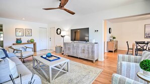 A spacious living room with a ceiling fan, a large TV, and a dining area with a table and chairs. - Relaxing Condo w/ Screened-in Lanai, 4 Mi to Beach (Naples)