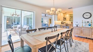 A spacious dining area with a large wooden table, multiple chairs, and a chandelier. - Relaxing Condo w/ Screened-in Lanai, 4 Mi to Beach (Naples)