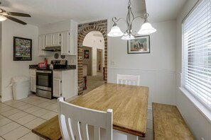 Une cuisine avec des meubles blancs, une table à manger en bois et un four encastré.