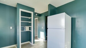 A kitchen with teal walls, a white refrigerator, and a white door leading to a hallway. - Walkable Hopkinsville Home w/ Yard! (Hopkinsville)
