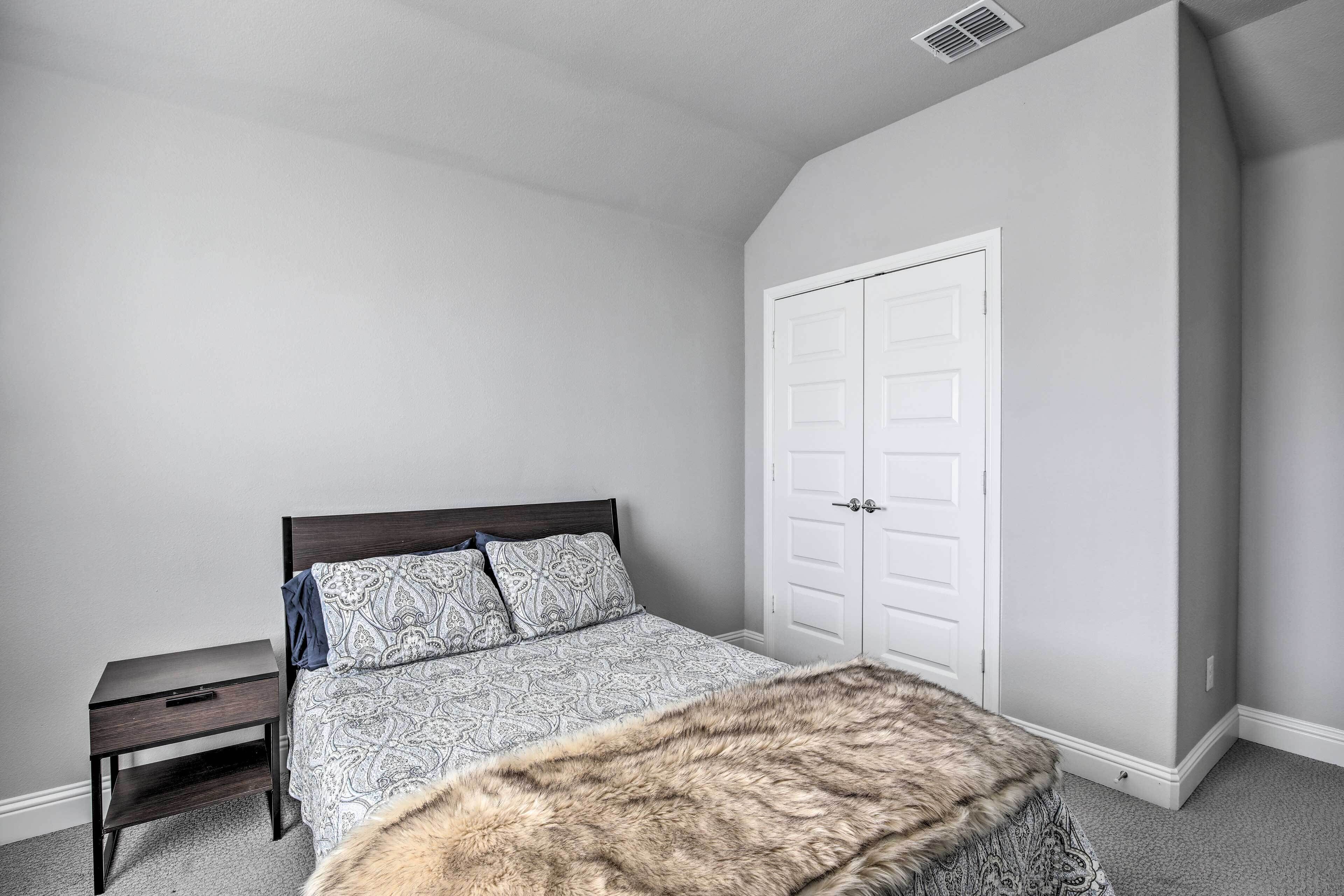 A bedroom with a bed, a nightstand, a wardrobe, and a fur throw.