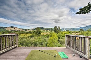 Eine Holzterrasse mit einem Putting-Green aus künstlichem Rasen, einem Golfschläger und einem Golfball.