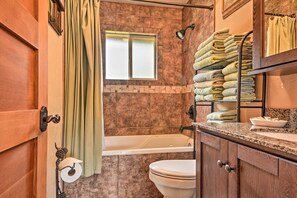 Ein Badezimmer mit Badewanne, Toilette und einem Handtuchhalter mit ordentlich gefalteten Handtüchern.