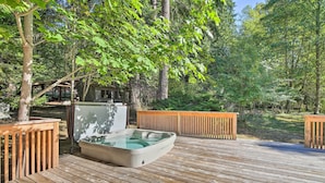 A hot tub on a wooden deck surrounded by trees.