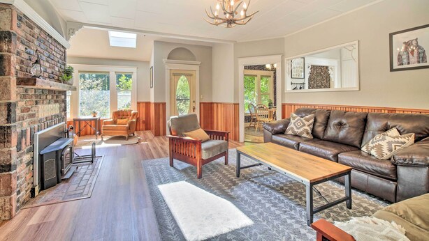 A spacious living room with a fireplace, leather sofa, and a large mirror.