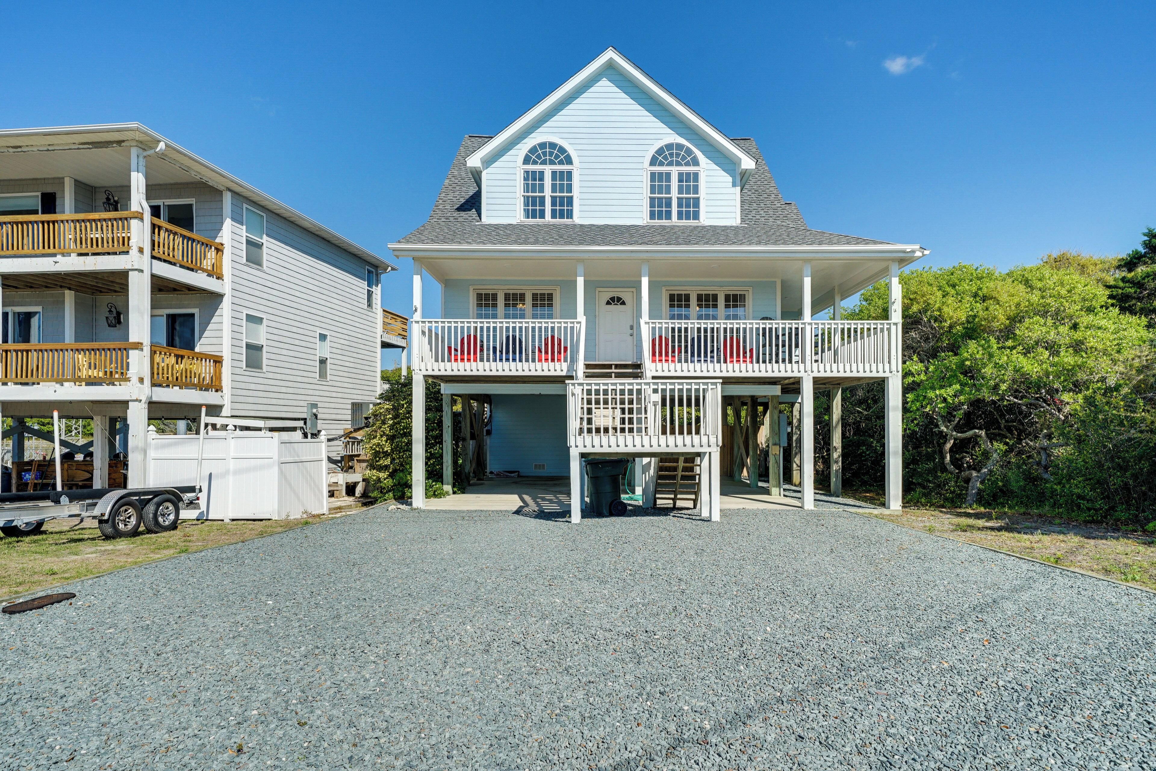 A two-story house with a balcony, a garage, and a gravel driveway.