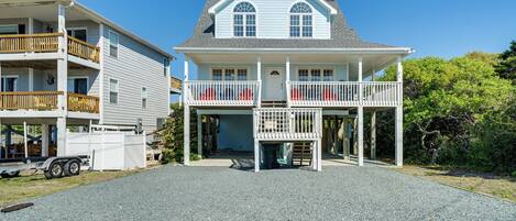 A two-story house with a balcony, a garage, and a gravel driveway.