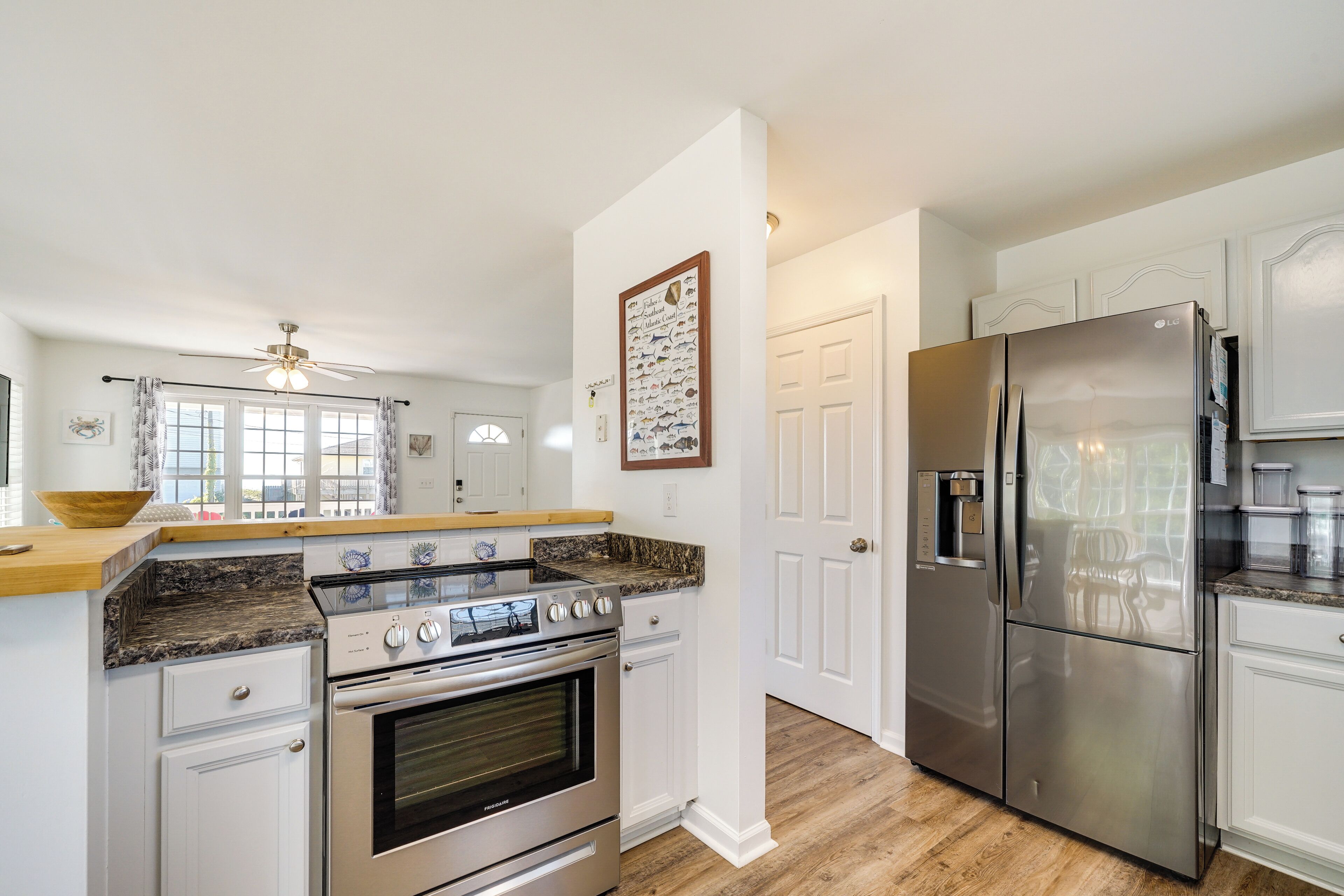 A modern kitchen with white cabinetry, stainless steel appliances, and a granite countertop.