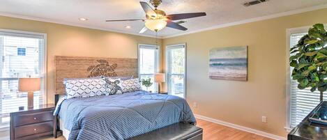 Une chambre à coucher avec un lit, un ventilateur de plafond, une table de chevet, un banc et une fenêtre.