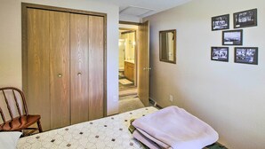 A bedroom with a wooden wardrobe, a bed with a patterned bedspread, and a wall with framed photos. - Waterfront Friendship Home w/ Private Pier! (Friendship)