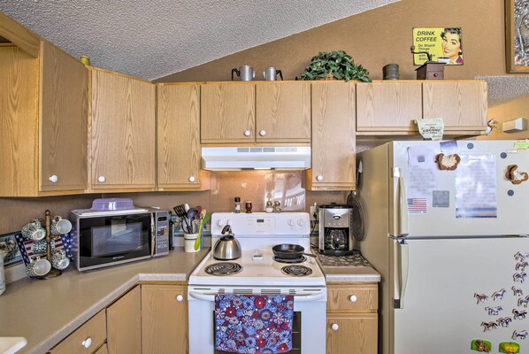 A kitchen with wooden cabinets, a microwave, stove, refrigerator, and various kitchen appliances. - Waterfront Friendship Home w/ Private Pier! (Friendship)