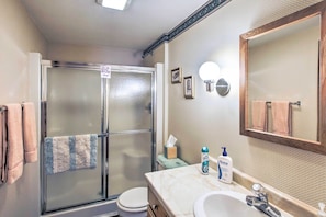A bathroom with a glass-enclosed shower, a sink with a mirror, and a toilet. - Waterfront Friendship Home w/ Private Pier! (Friendship)