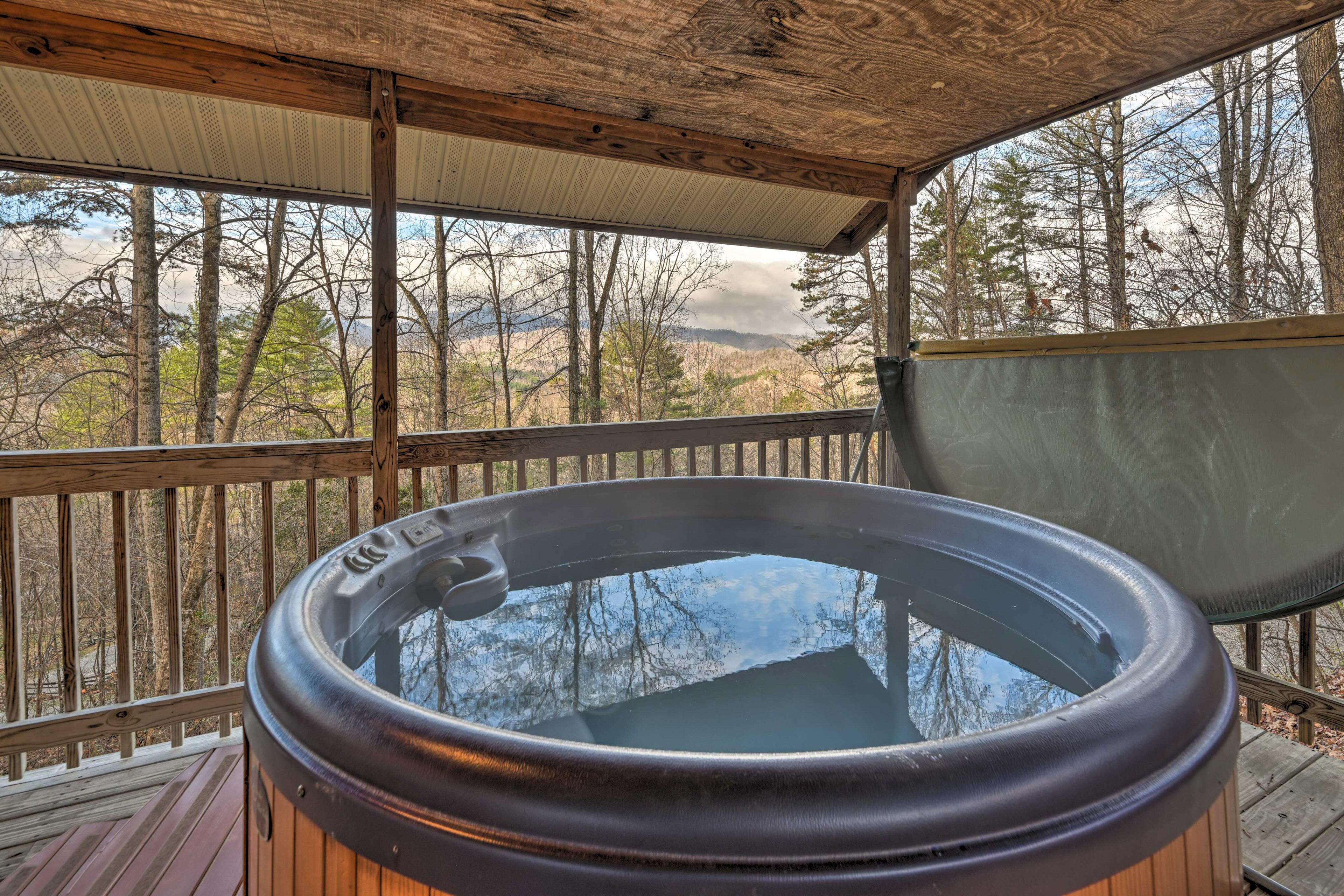Un bain à remous sur une terrasse en bois, avec vue sur les arbres et les montagnes.