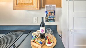 A kitchen counter with a wine bottle, glasses, a tray with snacks, and a corkboard with a calendar. - Historic Staunton Home ~ 1 Mi to Downtown! (Staunton)