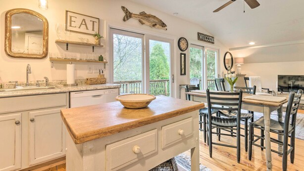 A kitchen with a wooden countertop, white cabinets, and a dining area with a table and chairs.
