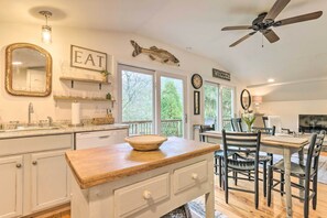 A kitchen with a wooden countertop, white cabinets, and a dining area with a table and chairs.