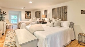 A bedroom with two beds, a bedside table, a lamp, and a window.