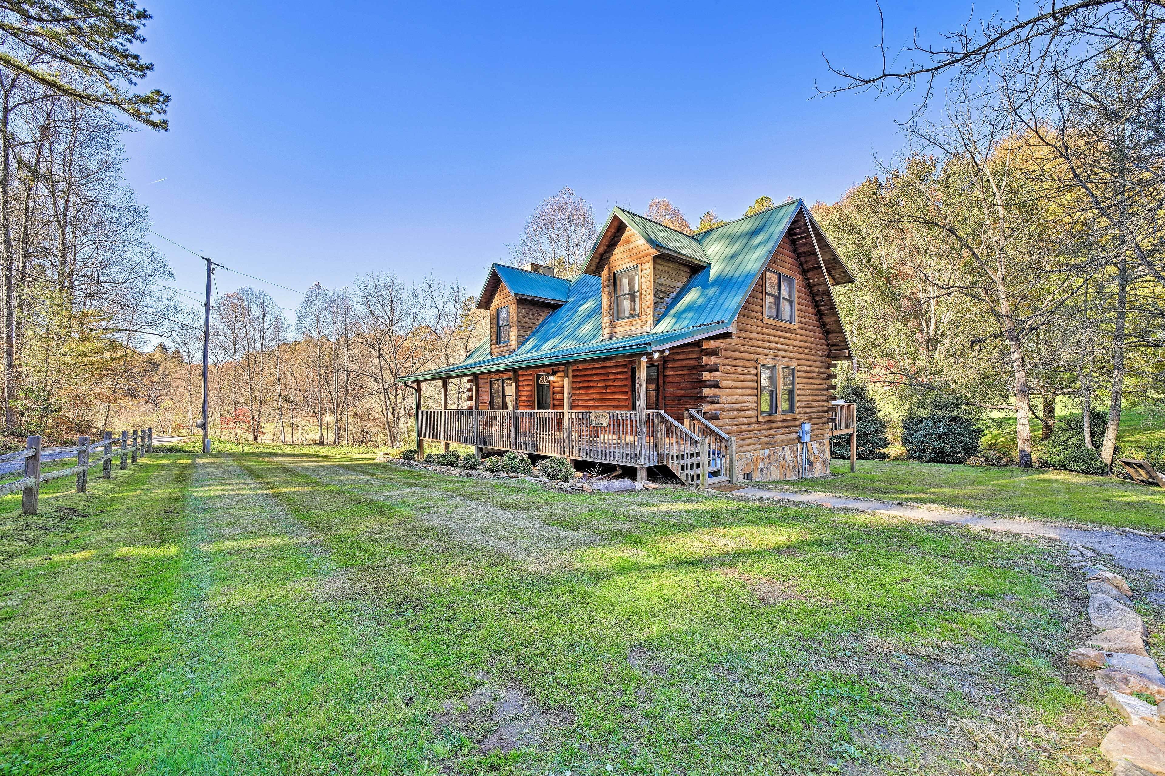 A log cabin with a metal roof, a porch, and a stone pathway leading to it.
