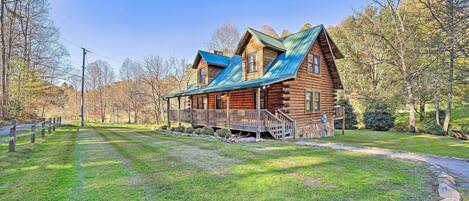 A log cabin with a metal roof, a porch, and a stone pathway leading to it.