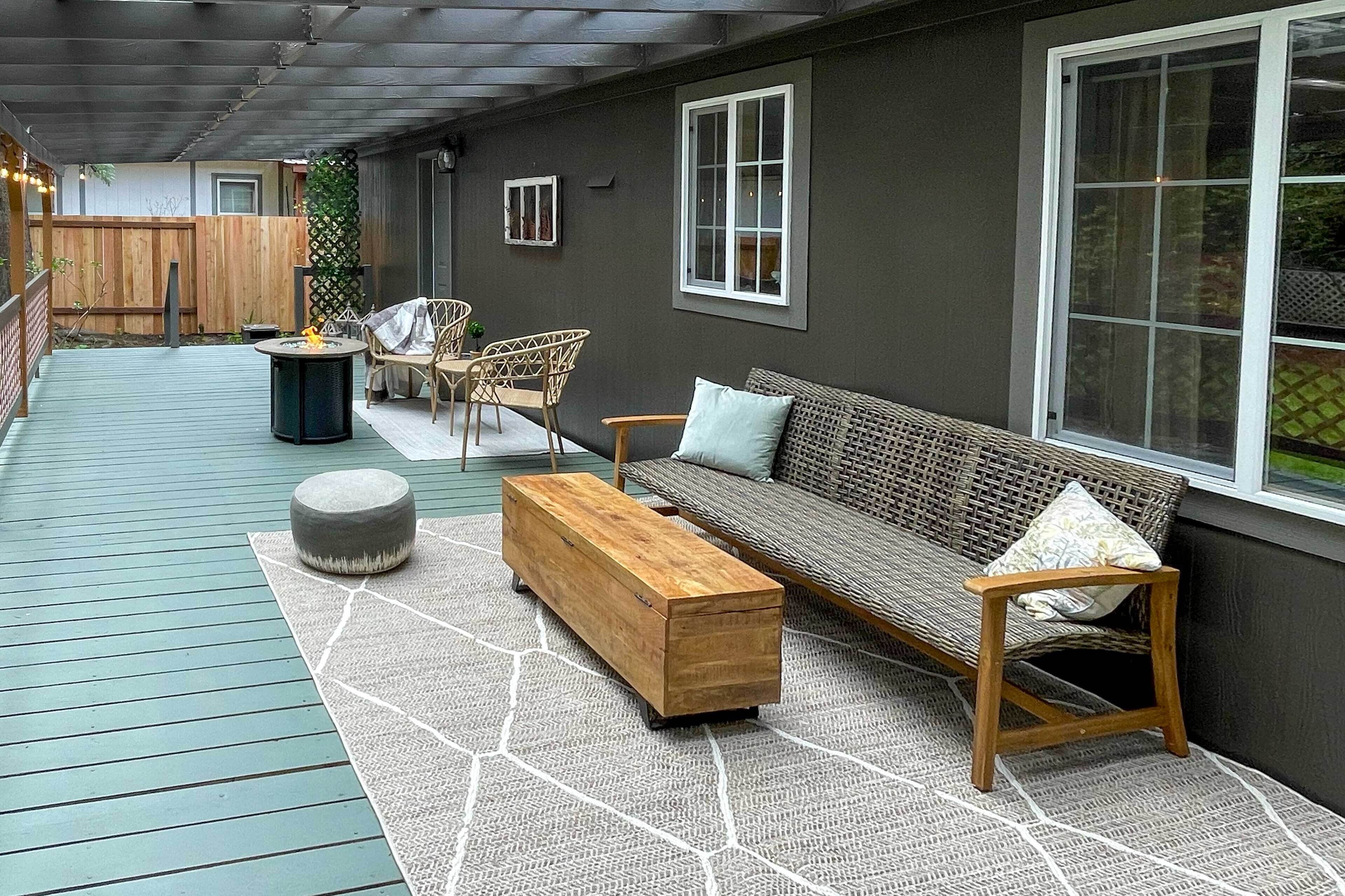 A covered patio with a wooden bench, a sofa, and a small table.