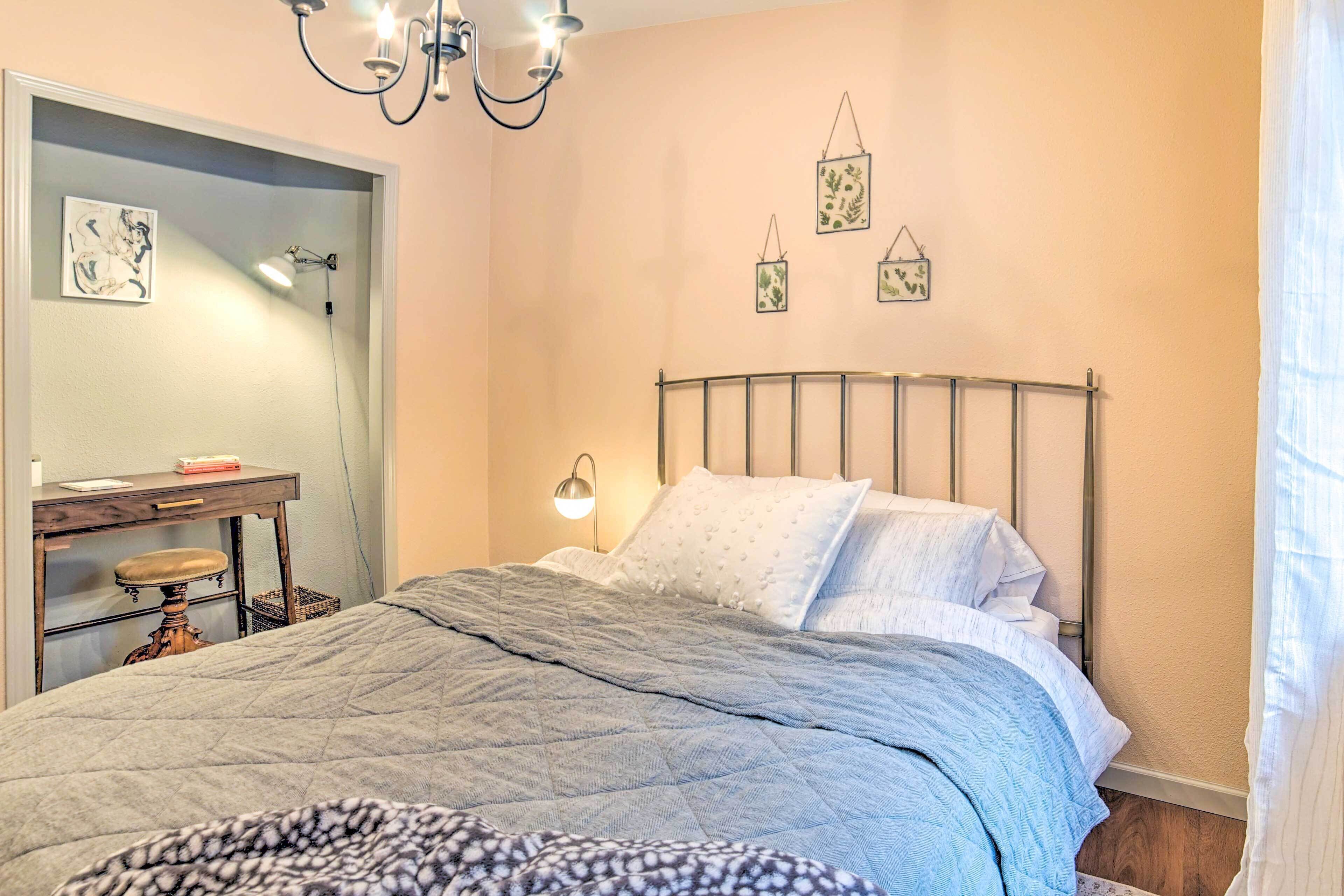 A bedroom with a bed, bedside table, lamp, and wall art.