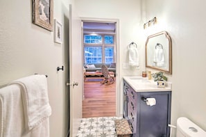A bathroom with a toilet, sink, and a window with a view of a wooden deck.