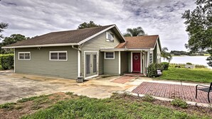 A two-story house with a front porch, a red door, and a view of a lake. - Historic Lakefront Gem ~ 6 Mi to Bok Tower Gardens (Lake Wales)