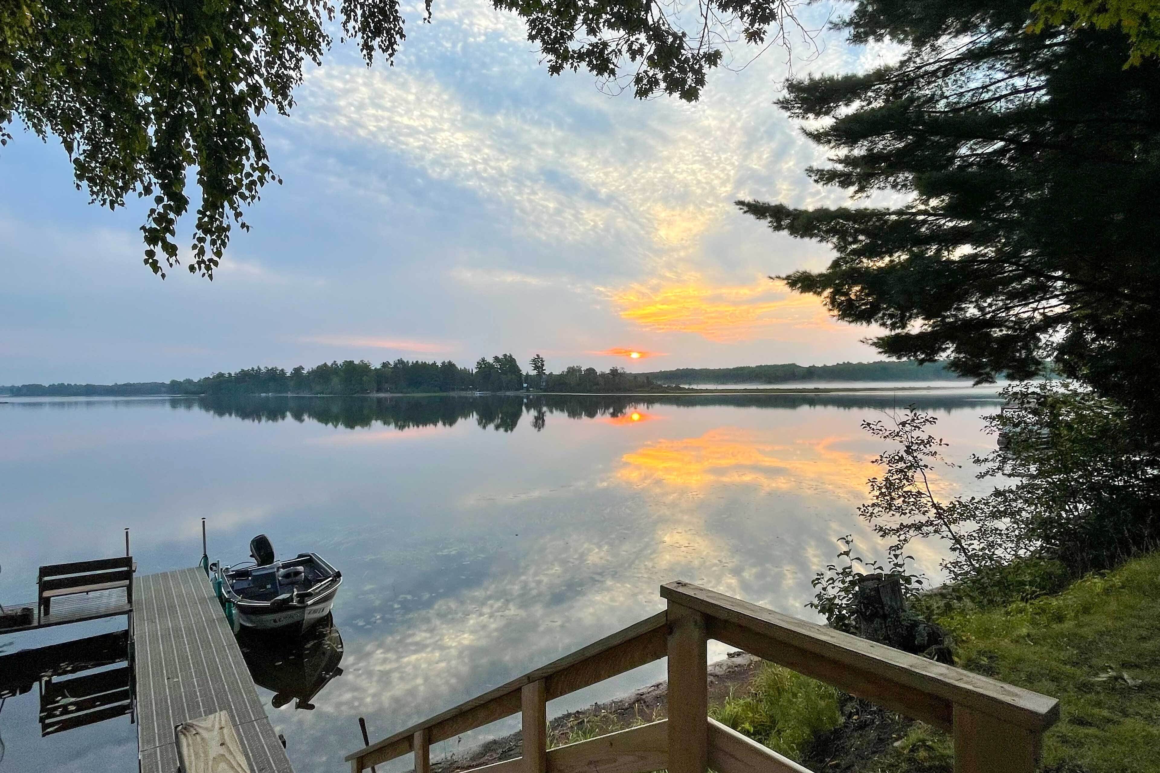 A wooden dock extending into calm water with a boat docked at the end.