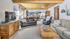 A spacious living area with a wooden ceiling, a television on a wooden cabinet, a leather sofa, and a beige sofa. - Lakefront Mercer Home: Private Dock & Kayaks! (Mercer)