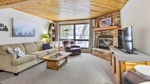 A cozy living room with a wooden ceiling, a fireplace, a television, and a sofa. - Lakefront Mercer Home: Private Dock & Kayaks! (Mercer)