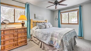 A bedroom with a bed, dresser, ceiling fan, and large windows. - Lakefront Mercer Home: Private Dock & Kayaks! (Mercer)