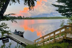 A wooden dock extending into calm water with a boat moored at the end. - Lakefront Mercer Home: Private Dock & Kayaks! (Mercer)