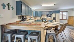 A modern kitchen with blue cabinets, a central island with stools, and a dining area with chairs. - Lakefront Mercer Home: Private Dock & Kayaks! (Mercer)