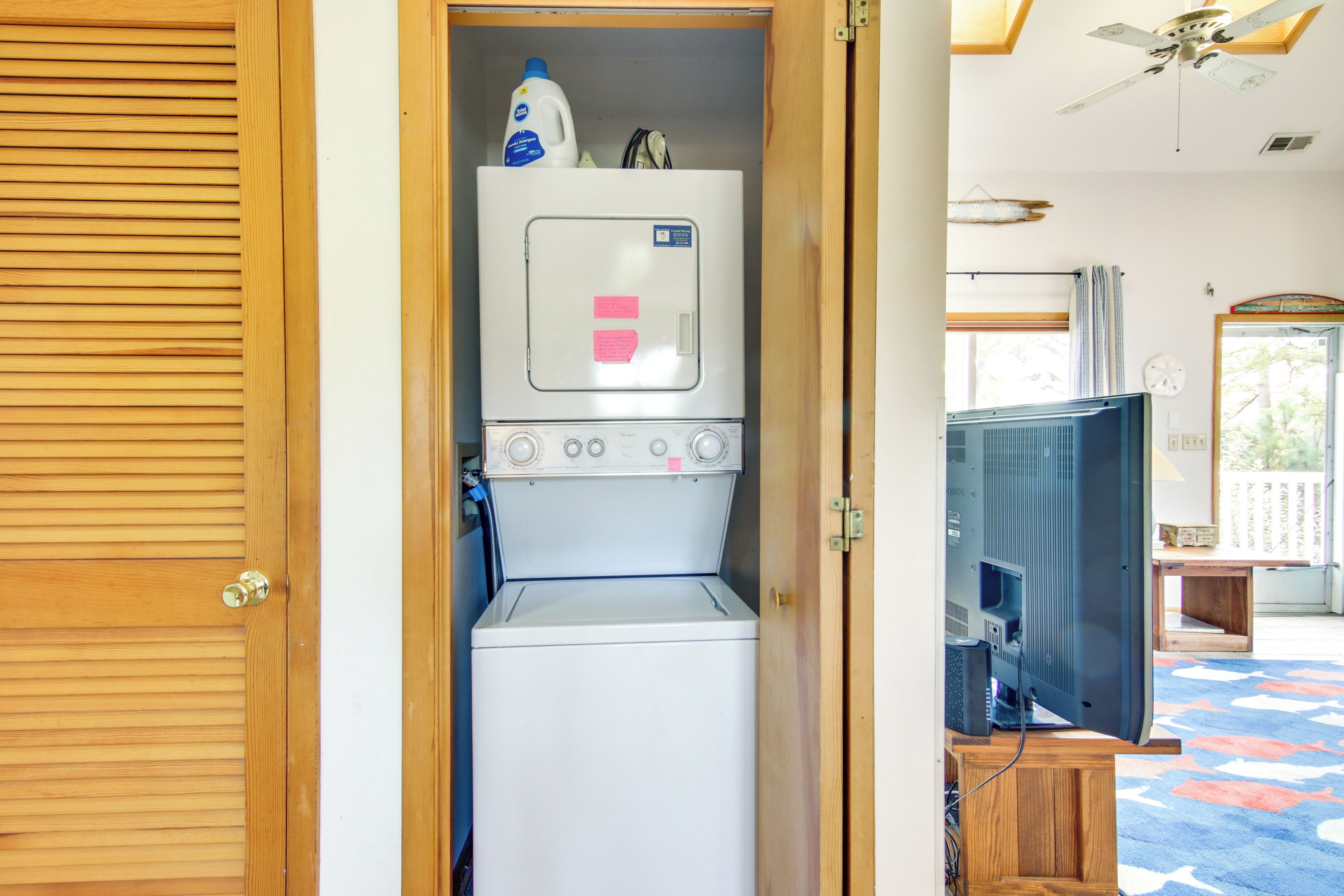 A laundry room with a washing machine and dryer, a television, and a ceiling fan.