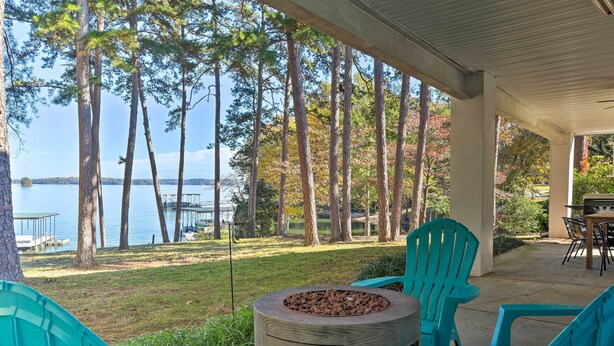 A covered patio with turquoise chairs, a fire pit, and a view of a lake and trees. - Anglers Paradise, 1 Mi to Broyles Recreation Area (Townville)