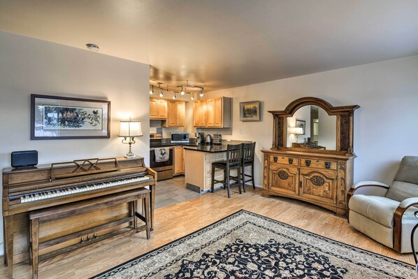Amplia sala de estar con un piano, una mesa de comedor, un sofá y un espejo grande.
