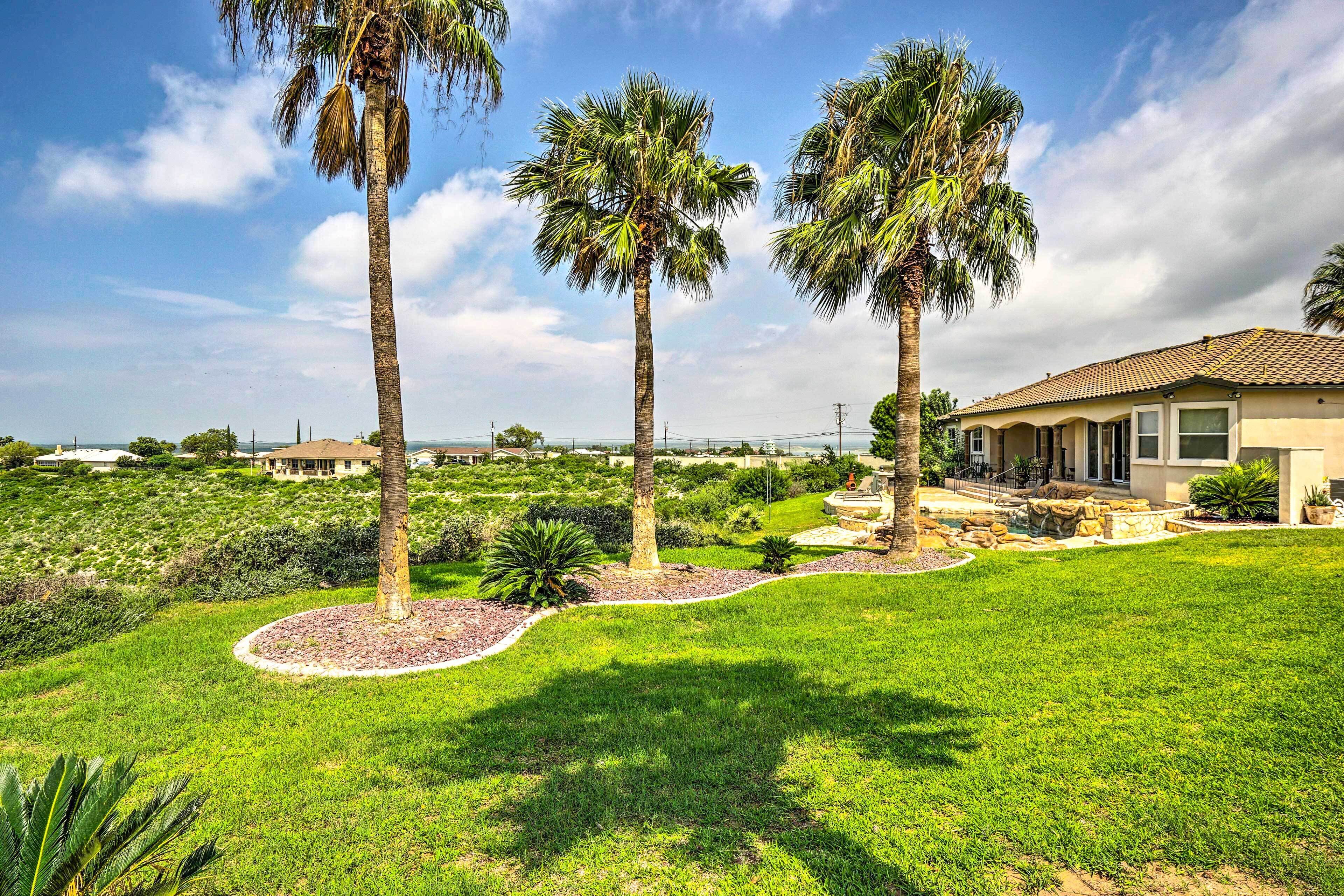 A residential area with palm trees, a well-maintained lawn, and a house with a tiled roof.