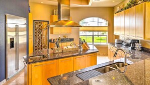 A modern kitchen with a stainless steel refrigerator, granite countertops, and wooden cabinets. - Luxury Del Rio Home w/ Pool & Lake Views! (Del Rio)
