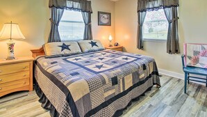 A bedroom with a large bed, two bedside tables, a nightstand, a chair, and a window with curtains.