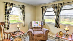 A cozy room with a brown leather armchair, a wooden chair, and a small table with a lamp and a clock.