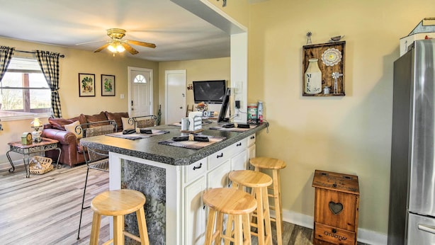 A kitchen with a central island, bar stools, a refrigerator, and a television.