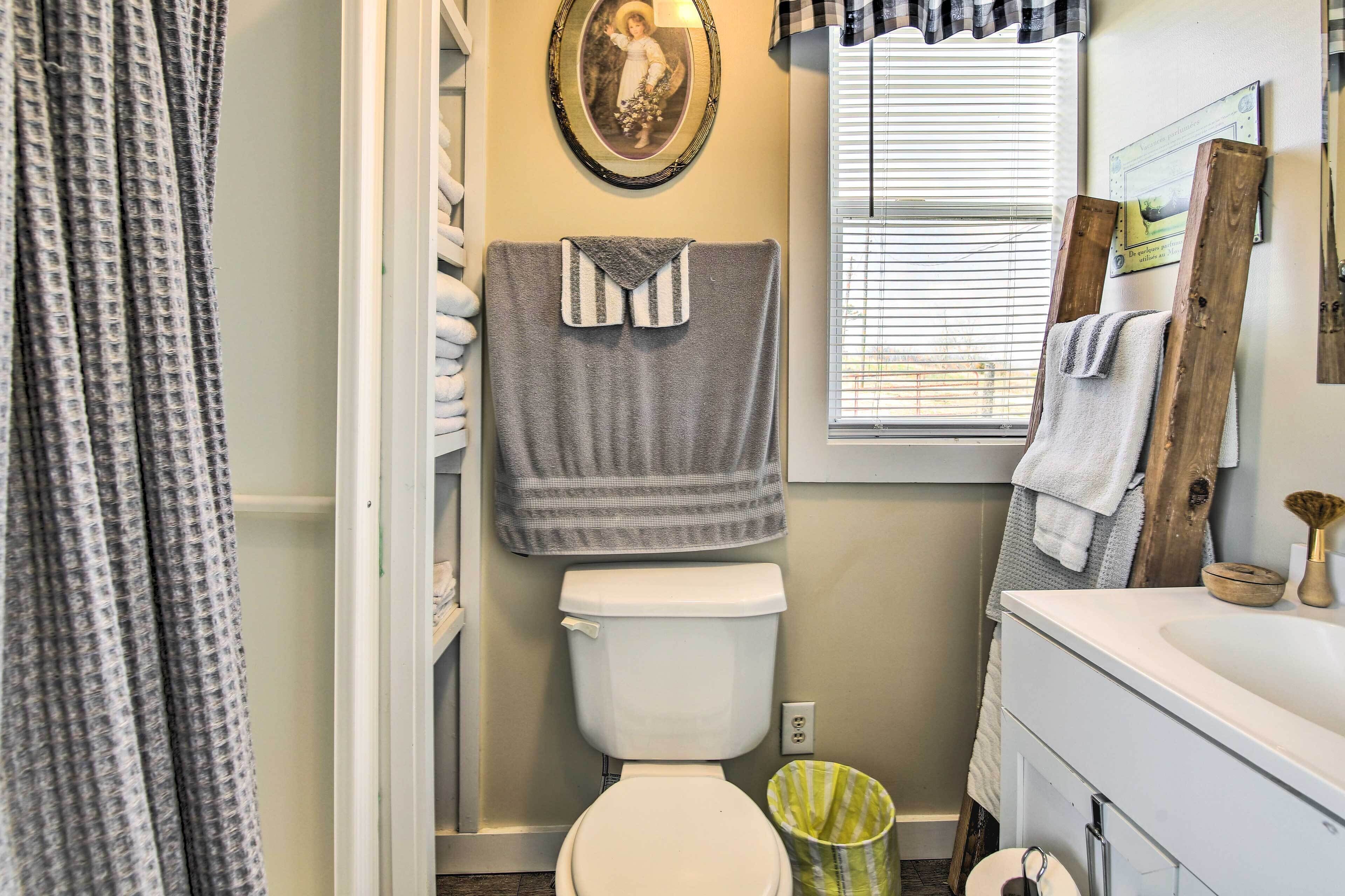 A bathroom with a toilet, a sink, a mirror, and a window with blinds.