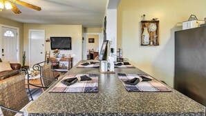 A kitchen with granite countertops, a dining table with placemats, and a refrigerator.