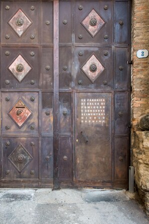 A large, ornate metal door with a plaque and a number '2' sign on the wall.